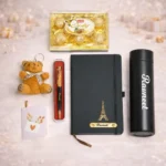 Full view of Tohfa Riwaz luxury gift box containing a personalized black diary, custom water bottle, gold-flecked pen, Ferrero-style chocolates, and a small brown teddy bear.