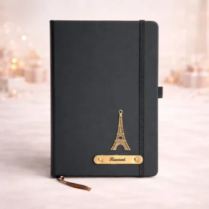 Black stainless steel water bottle with custom name engraving standing next to a box of gold-wrapped chocolates and a cute plush teddy.